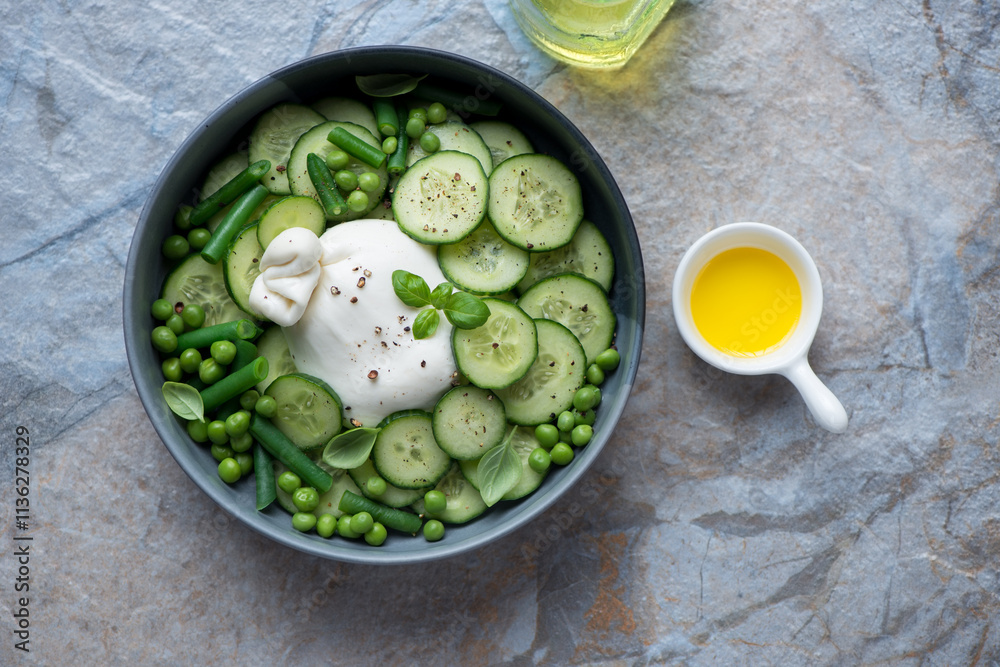 Bowl of salad with burrata, fresh cucumber, green peas and basil, above view on a beige and blue stone background, horizontal shot Bowl of salad with burrata, fresh cucumber, green peas and basil, above view on a beige and blue stone background, horizontal shot