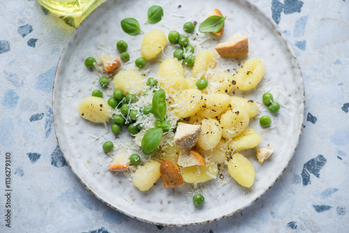 Italian gnocchi served with different types of cheese and green peas on a grey plate, horizontal shot, elevated view, middle closeup