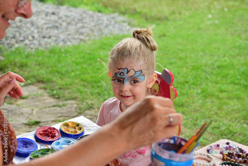 The little girl enjoys how they paint a colorful picture on her face