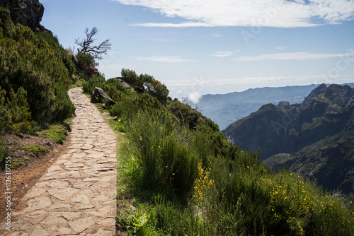 Tourists walking stony hiking trail on the edge of the mountain, Madeira, Portugal photo