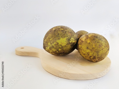 three round Bael or wood apples on a white background