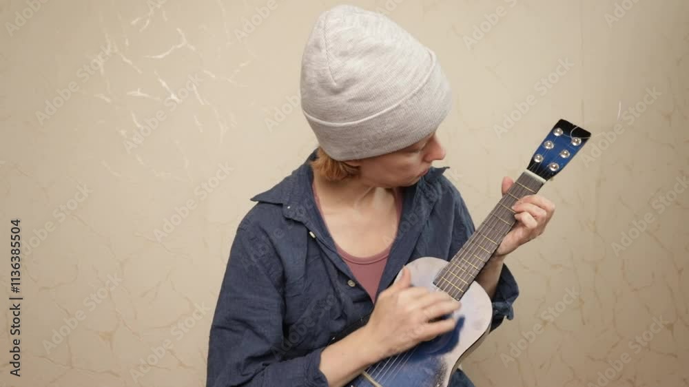 Guitalele, musician plays an acoustic instrument, classical music lesson with acoustic strings, singer in a home practice session, person studying chords and melody.