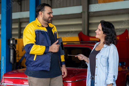 satisfied caucasian woman client giving money to young asian man for car problem service,concept for auto service business,customer satisfaction,car insurance