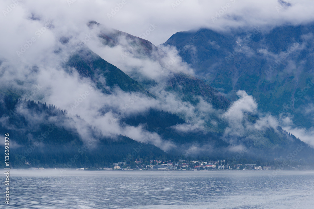 Obraz premium View from a tourist boat at the misty Kenai Mountains and the town of Seward in the distance, Kenai Peninsula, Alaska, USA 