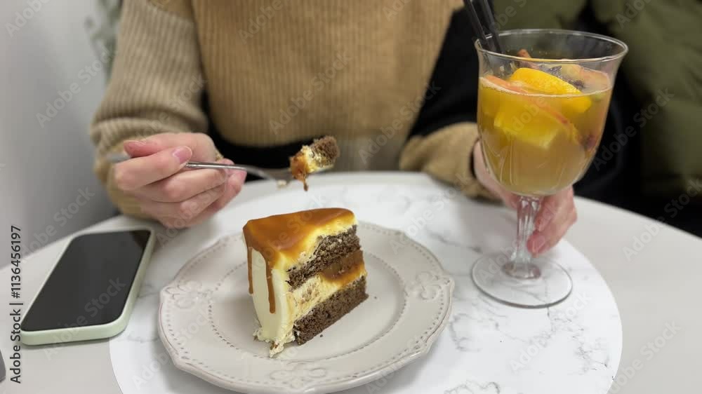 Delightful moments of a woman savoring cake and sipping fruit juice in a cozy cafe