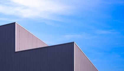 Factory warehouse building with light and shadow on geometric black metal wall surface against blue sky background, Exterior architecture minimal design backdrop