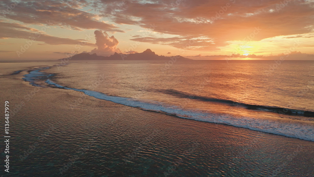 Obraz premium Golden sunset colorful sky over the ocean waves rolling towards the beach shore, picturesque tropical scene in Tahiti, French Polynesia. Remote wild nature paradise, exotic summer travel background
