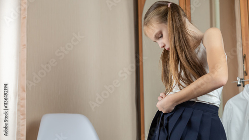 Little girl getting dressed school uniform in her room and preparing go to school