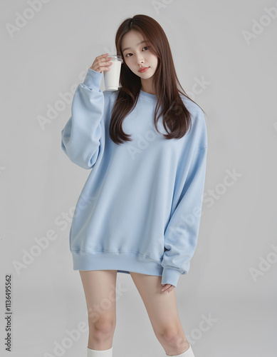 Full Body Photo of Asian Girl in Light Blue Loose Sweatshirt and White Short Skirt holding coffee cup Posing Against Simple Background	
