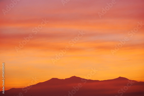 Fototapeta Naklejka Na Ścianę i Meble -  Early morning light sky before sunrise. Vivid warm yellow, orange and brown light on mountainous horizon. Panoramic sky with colorful pastel tone colors for background.