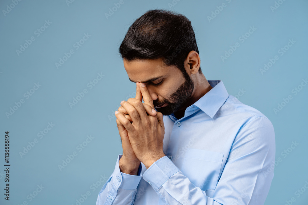 Portrait of bearded, middle aged Indian man holding hands praying with closed eyes Portrait of bearded, middle aged Indian man holding hands praying with closed eyes