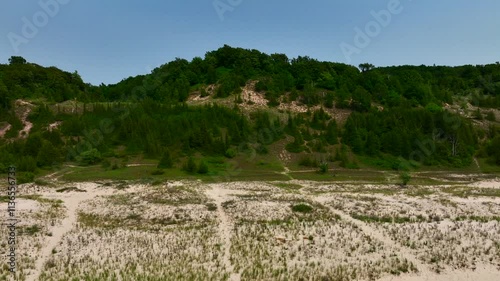 Aerial Drone footage of the Lake Michigan Shoreline in Elberta Michigan near Frankfort. A beautiful sunny summer day with tree covered sand dunes, waves and beach visible.