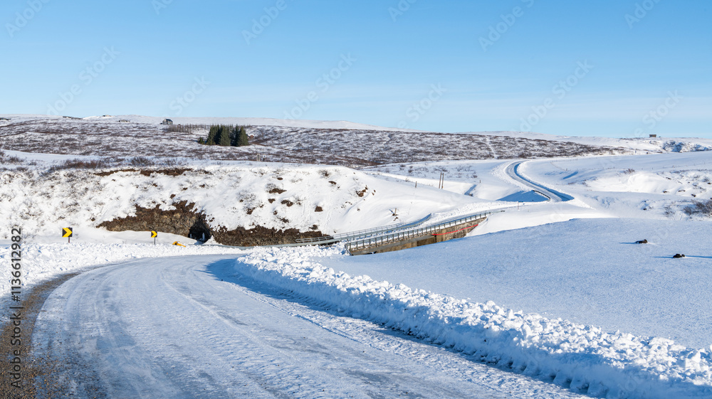 bridge with metal guardrail guard rail during winter, covered with snow over the Hölmsa river in Iceland. sunny winter day, roadtrip. Snowy landscape, road in foreground bridge with metal guardrail guard rail during winter, covered with snow over the Hölmsa river in Iceland. sunny winter day, roadtrip. Snowy landscape, road in foreground