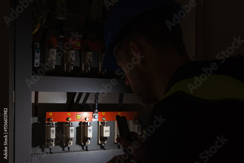 Worker in helmet shine with light and control circuit breaker. Electricity blackout, maintenance background