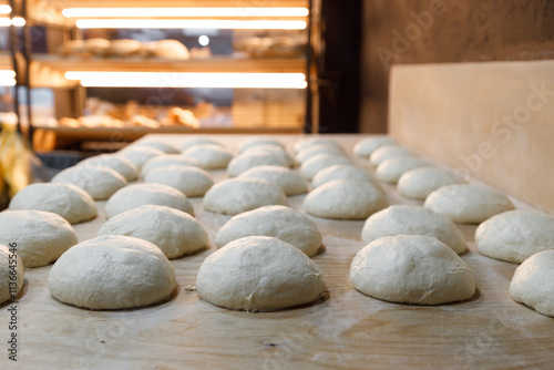 A chunk of dough is resting on a wooden table in a bakery