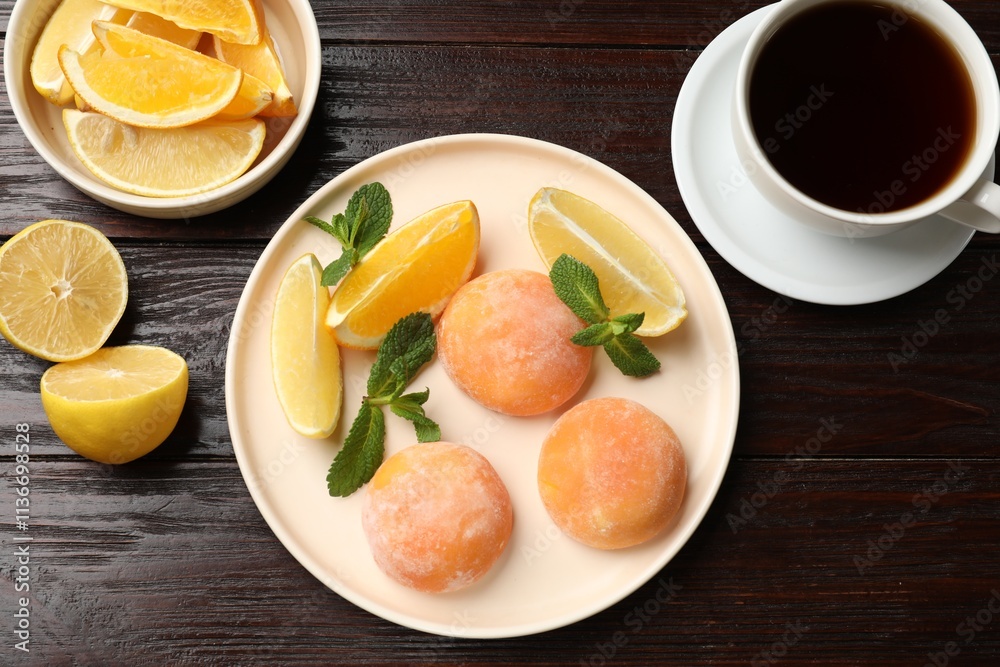 Tasty mochi, cut orange, lemon and mint served with tea on wooden table, flat lay
