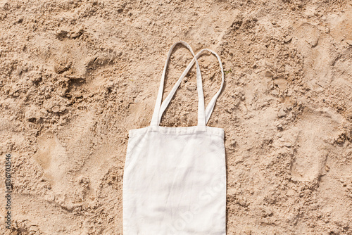 White cotton or mesh bag on beach sand background. Zero waste, no plastic, eco friendly shopping, recycling concept. Blank mockup shopper with place for artwork or text. Flat lay, copy space photo