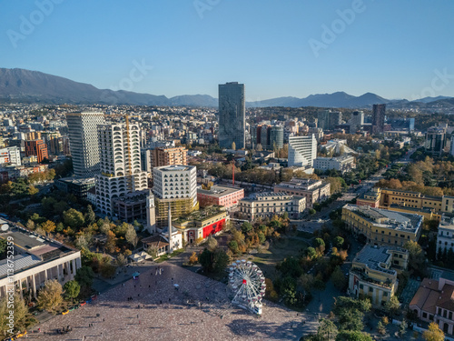 Aerial view of Tirana, Albania, showcasing modern architecture, Skanderbeg Square, and surrounding mountains under a clear blue sky. photo