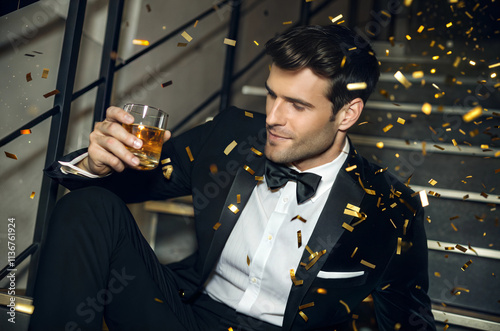 Elegant Celebration Man in Tuxedo Enjoying Drink Amidst Confetti