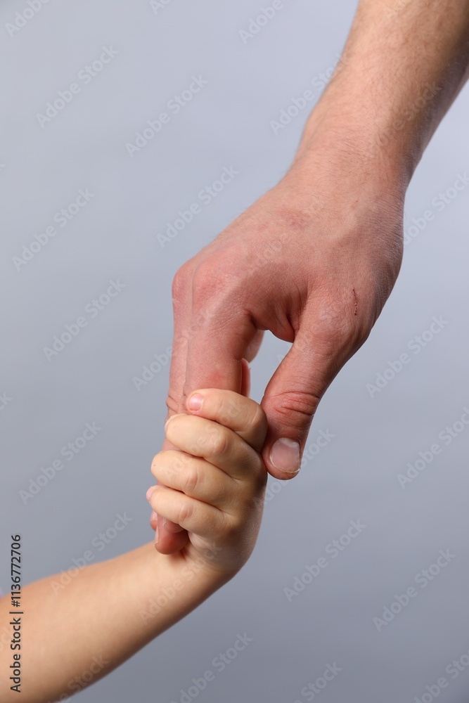 Father and child holding hands on grey background, closeup Father and child holding hands on grey background, closeup