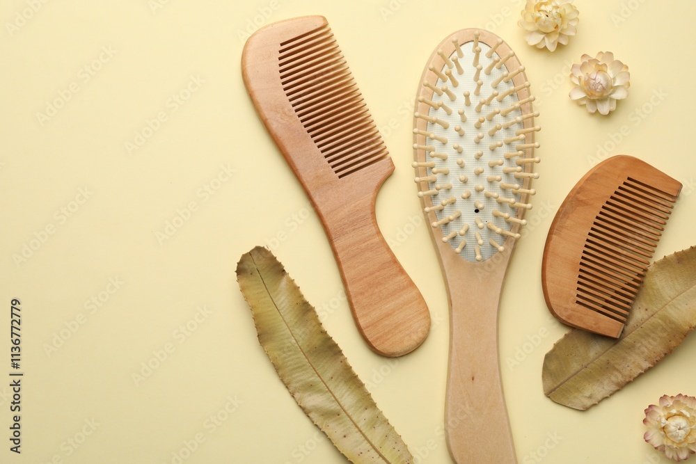 Wooden hair brush, combs, flowers and leaves on beige background, flat lay. Space for text Wooden hair brush, combs, flowers and leaves on beige background, flat lay. Space for text