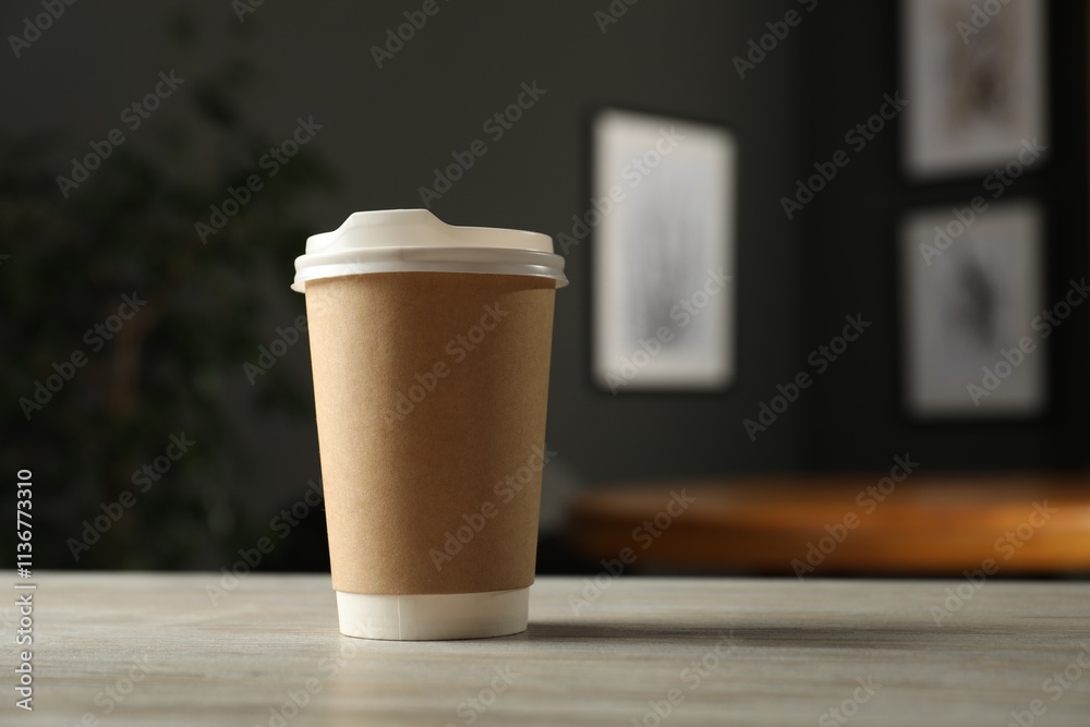 Paper cup on light wooden table in cafe, closeup. Mockup for design