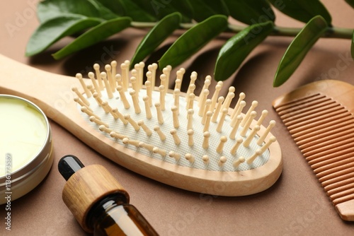 Wooden hair brush, comb, cosmetic products and green branch on dark beige background, closeup