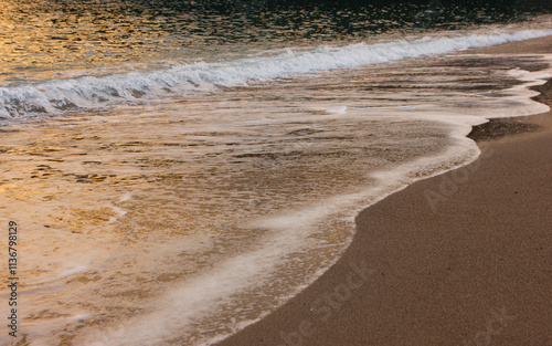 Fototapeta Naklejka Na Ścianę i Meble -  The wave breaks on the shore. White sea foam silhouette