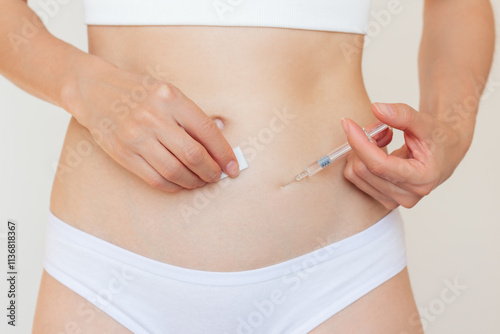 A young Caucasian woman in white underwear giving herself a subcutaneous injection into her stomach. Women's reproductive health. photo