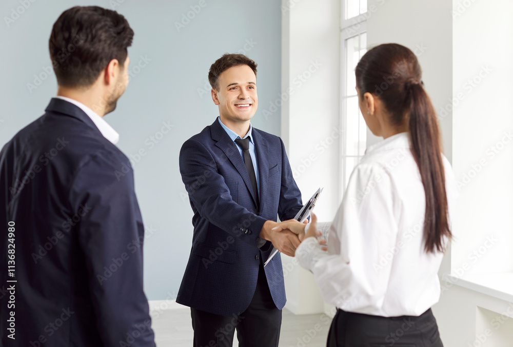 Young family couple buying new house or apartment, exchange handshake with relator. Happy homeowners, husband and wife shaking hands with professional real estate agent after making successful deal. Young family couple buying new house or apartment, exchange handshake with relator. Happy homeowners, husband and wife shaking hands with professional real estate agent after making successful deal.