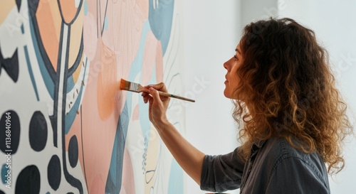Young caucasian female artist painting a colorful abstract mural