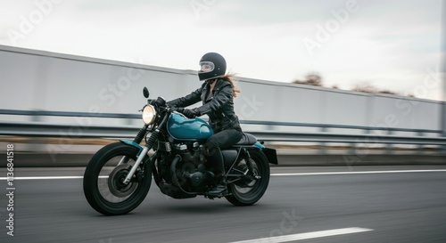 Female rider on blue motorcycle speeding on highway in black gear and helmet photo