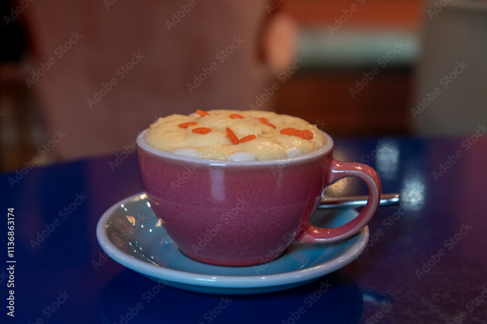 Close-up view of purple porcelain cup of pumpkin latte made from espresso, milk, whipped cream and caramel sprinkles standing on blue table in cafe or restaurant. Inspirational coffee drinks theme. Close-up view of purple porcelain cup of pumpkin latte made from espresso, milk, whipped cream and caramel sprinkles standing on blue table in cafe or restaurant. Inspirational coffee drinks theme.