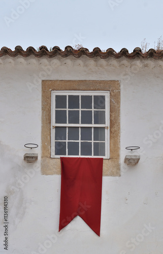 Window with red flag on an old white wall, medieval environment