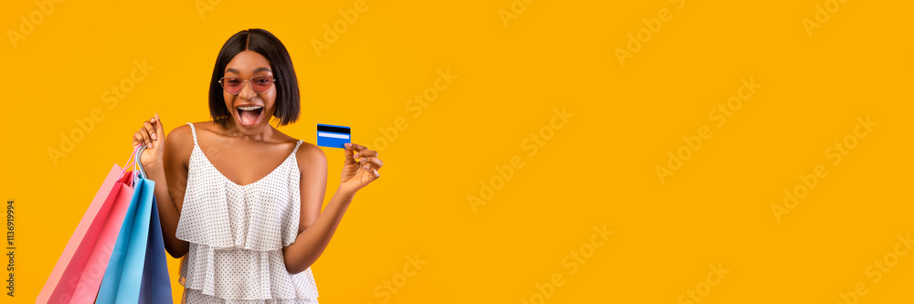 Summertime sales concept. Excited black woman with shopping bags showing credit card, shouting OMG on orange studio background. Overjoyed young lady using electronic money, copy space