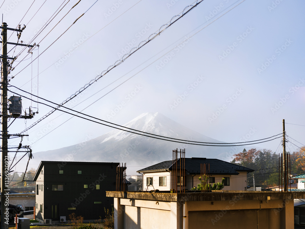 Fujiyoshida, Japan - November 21 2024: Looking up at snow capped mt fuji from the small town with honcho street and traditional japanese buildings and shops. Cool autumn weather with glowing sunlight Fujiyoshida, Japan - November 21 2024: Looking up at snow capped mt fuji from the small town with honcho street and traditional japanese buildings and shops. Cool autumn weather with glowing sunlight