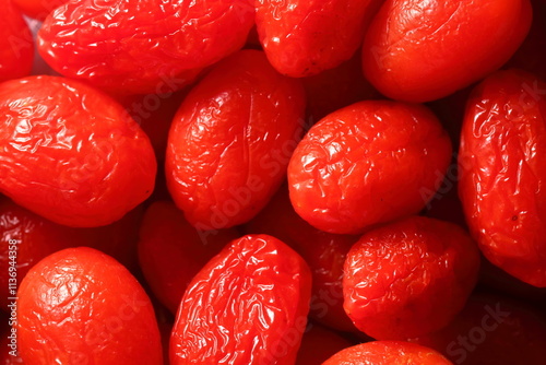 The image features a close-up of shriveled, wrinkled strawberry tomatoes with a dried skin texture, set against a dark background.  imperfect look of the tomatoes gives a sense of natural aging.
