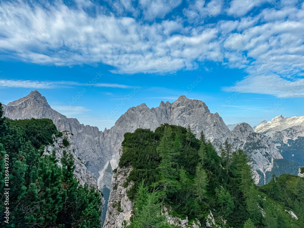 Obraz premium Jagged rock formation with scenic view of rugged mountain peak Prisank in majestic Julian Alps seen from Triglav National Park, Vrsic pass, Slovenia. Wanderlust wild Slovenian Alps. Sharp steep ridges