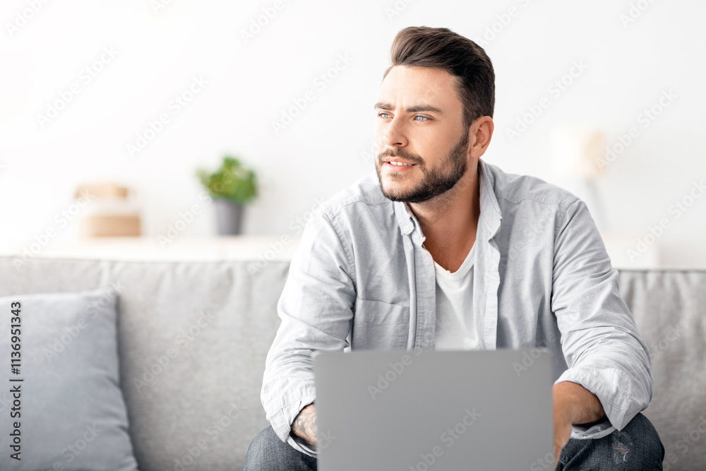 Millennial freelancer working on laptop and looking aside, thinking about successful business strategy or dreaming about holiday, sitting on sofa at home interior, free space Millennial freelancer working on laptop and looking aside, thinking about successful business strategy or dreaming about holiday, sitting on sofa at home interior, free space