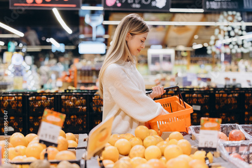 Slika na platnu Woman choosing grapefruit in supermarket fruit and vegetable section