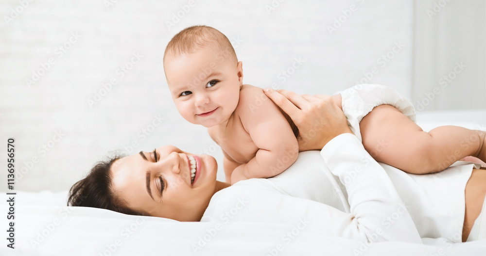 Family having fun together. Mom and baby boy in diaper playing in bedroom, panorama, copy space Family having fun together. Mom and baby boy in diaper playing in bedroom, panorama, copy space