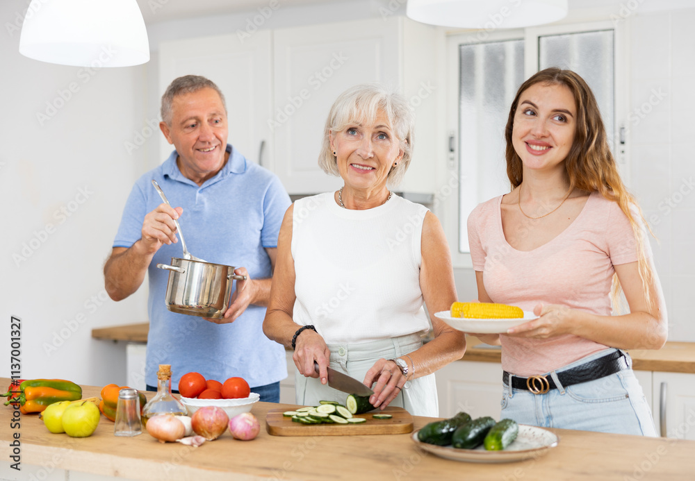 Happy smiling parents enjoy weekend cook with adult daughter in kitchen Happy smiling parents enjoy weekend cook with adult daughter in kitchen