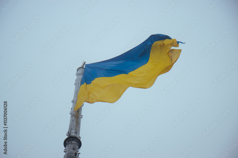 The Ukrainian flag gracefully waving high in the air on a foggy day, its vibrant yellow and blue colors standing as a testament to national resilience and pride.