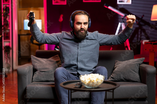 Cheerful gamer bragging after finally defeating all enemies while playing on gaming console. Joyful player congratulating himself after winning videogame using controller