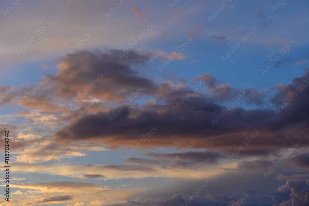 Fototapeta premium Dramatic evening sky filled with colorful clouds over a tranquil landscape at sunset