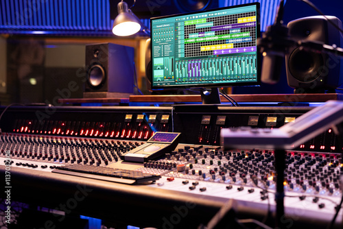 Control desk in professional music studio with motorized faders and knobs used in mixing and mastering tracks. Empty control room used in recording and producing songs, sound booth.