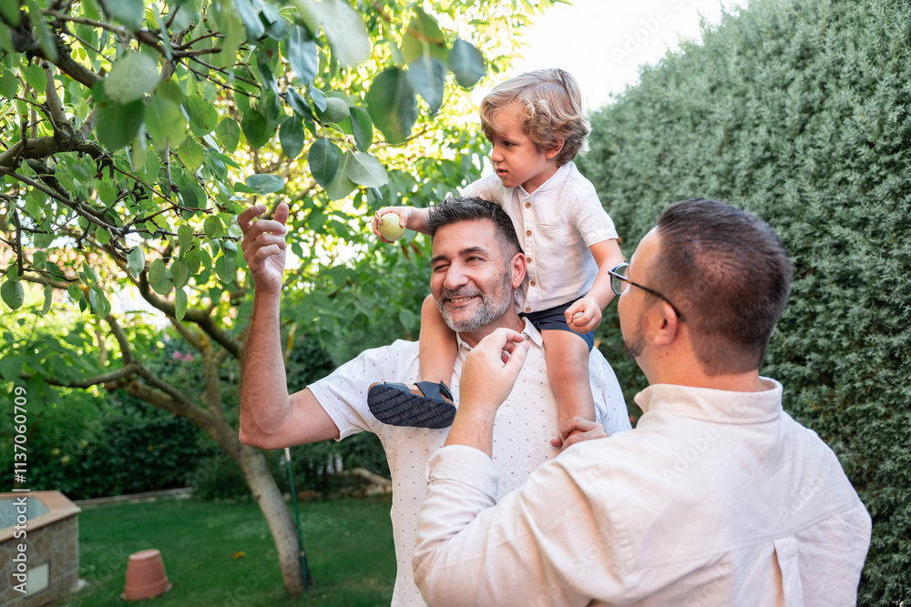 Loving moments of a gay family picking fruit in the garden Loving moments of a gay family picking fruit in the garden