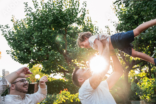 Gay couple playing together lifting their son outdoors photo