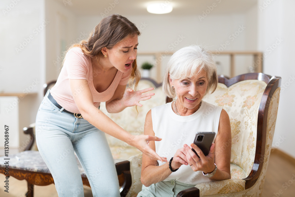 An adult daughter helps an elderly mother deal with a mobile phone An adult daughter helps an elderly mother deal with a mobile phone