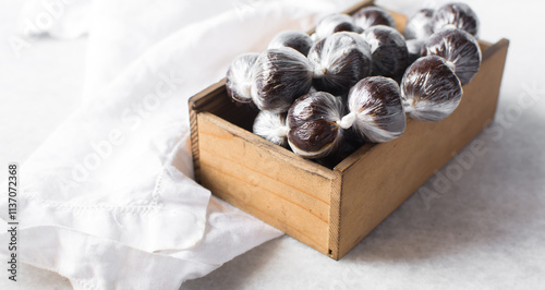 nigerian baba dudu candy in a brown wood box, top view of Ghana coconut candy or kube toffee candy, hard candy made with coconut milk and sugar on granite countertop photo